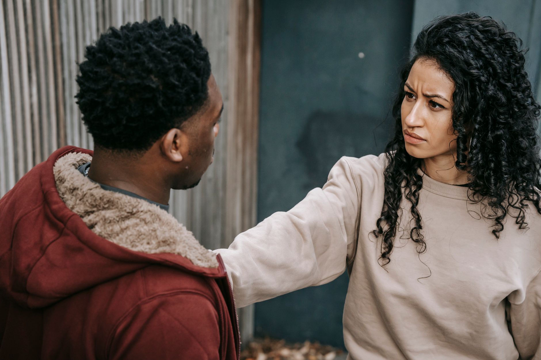 From above of dissatisfied ethnic woman with outstretched arm stopping African American man while having argue on street and looking at each other