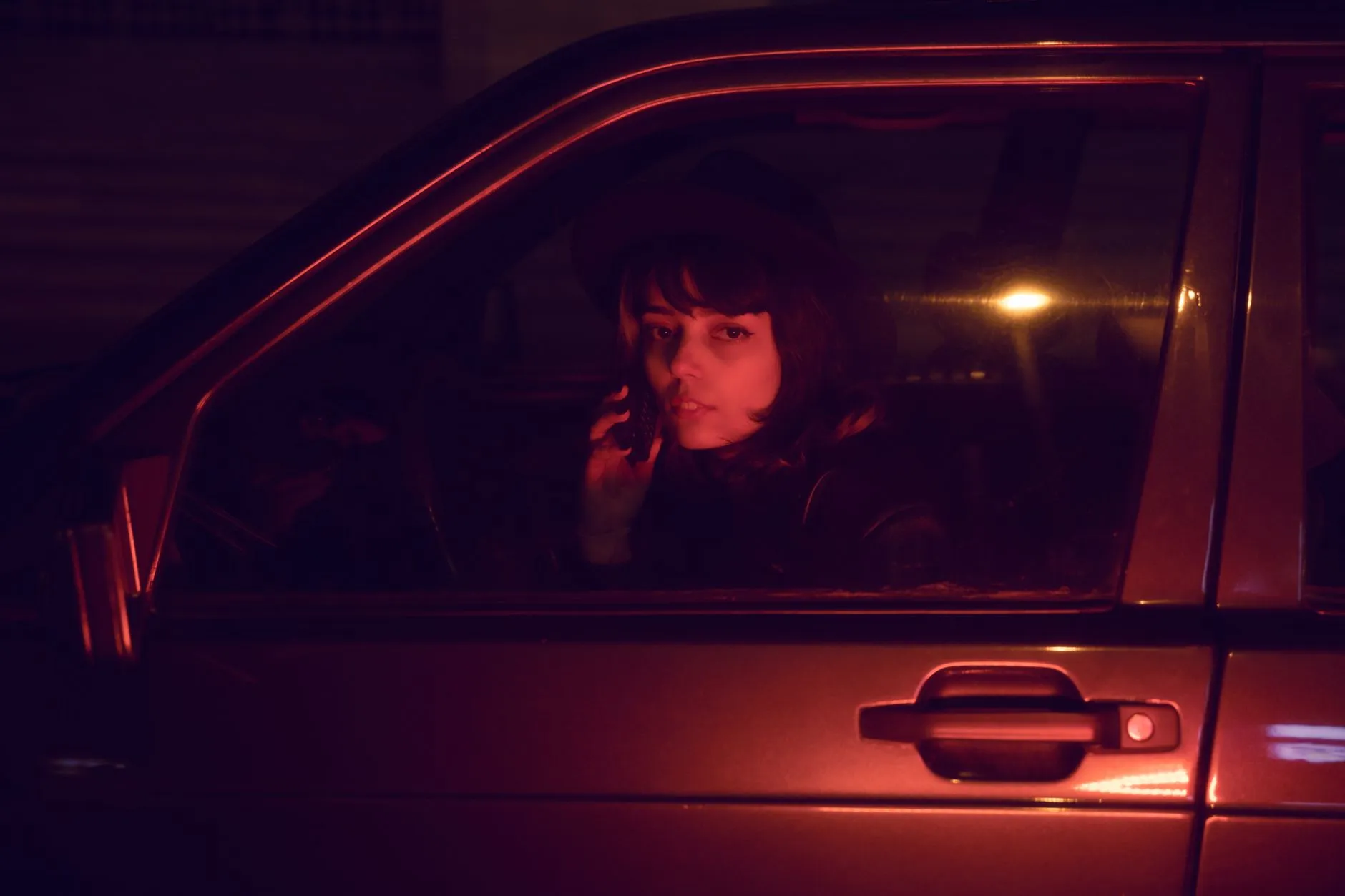 A woman in a car at night under dramatic lighting in İstanbul.
