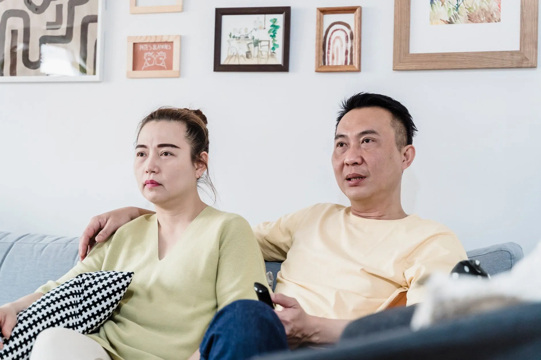 A couple sitting on a comfortable sofa at home in a cozy living room, enjoying a relaxed moment together.