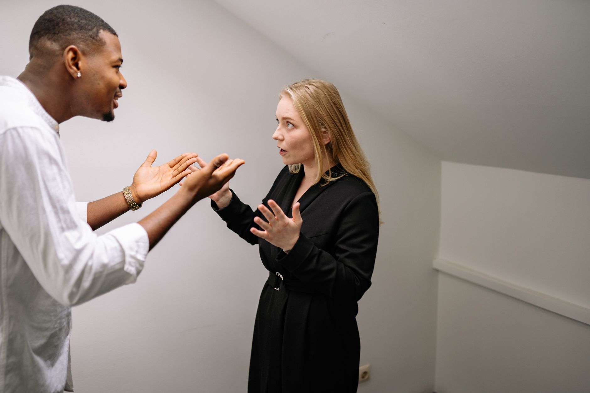 A man and woman having a heated discussion in a minimalistic indoor space.